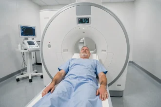 Patient homme allongé dans un scanner TEP (PET scan) lors d'un examen de contrôle oncologique en milieu hospitalier